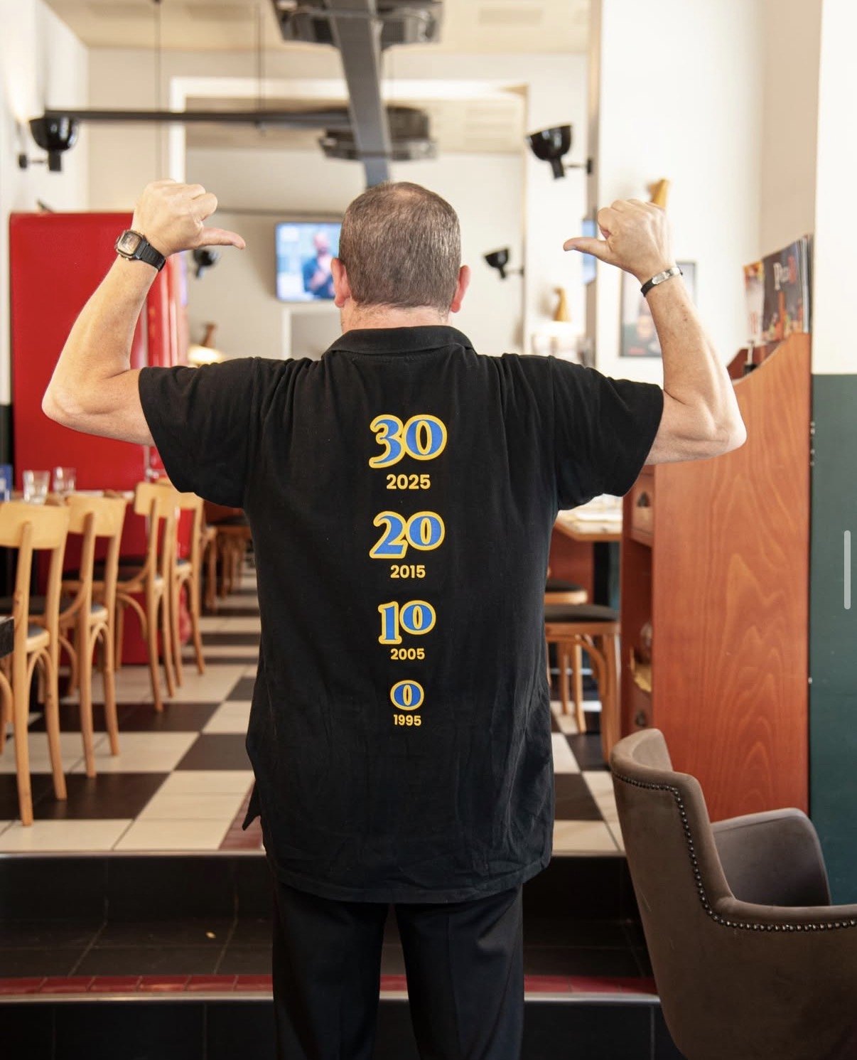 Membro dello staff PizzaRé di spalle con la maglia celebrativa dei 30 anni, nella sala del locale